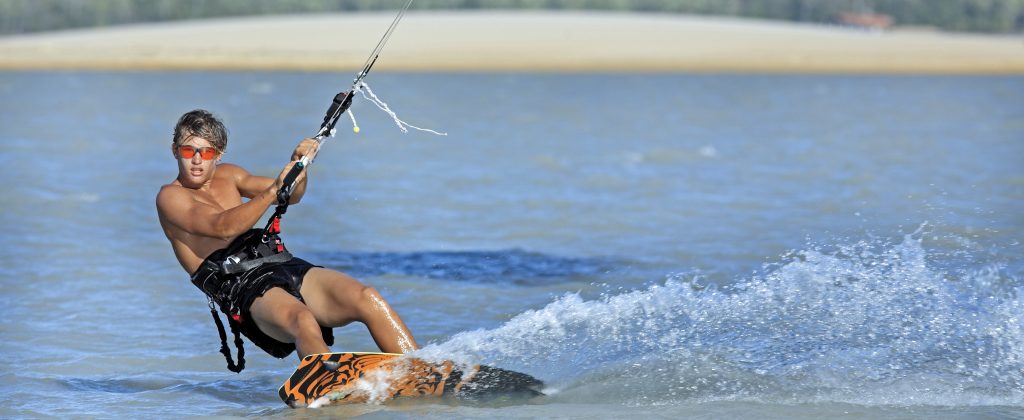 Kitesurfer rides across water.
