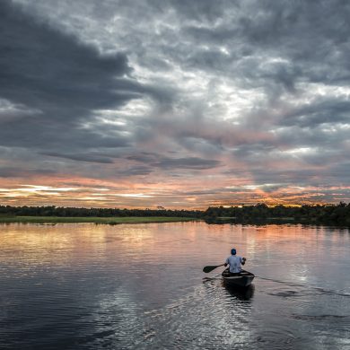 A sunset view of a boar paddling along the River Negro.