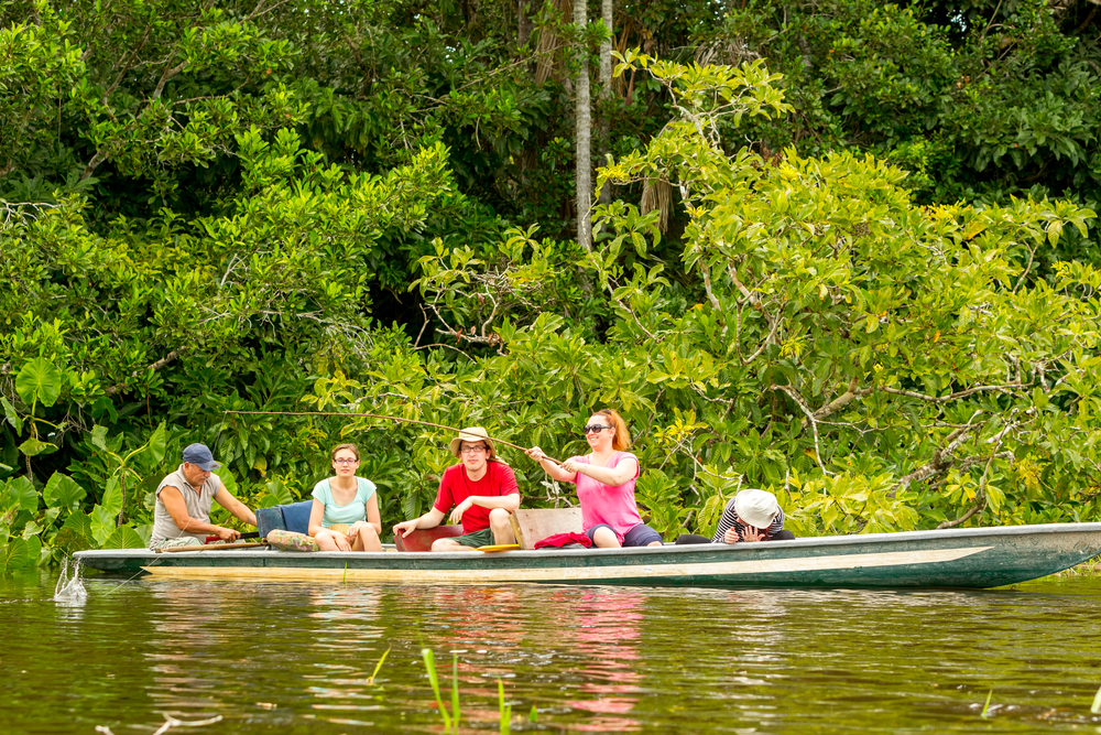 Some tourists piranha fishing from a boat accompanied by a guide on the Amazon river. 