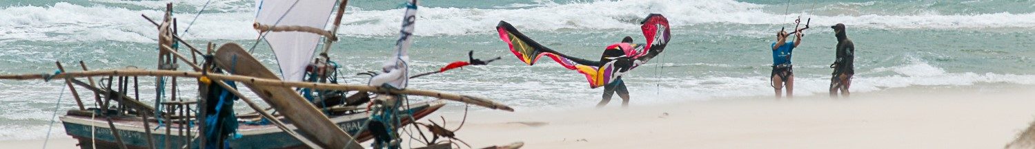 A kitesurfer emerges from the sea in windy conditions.